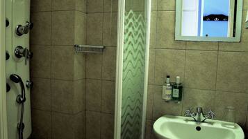 A bathroom with a shower, a sink, and a mirror.