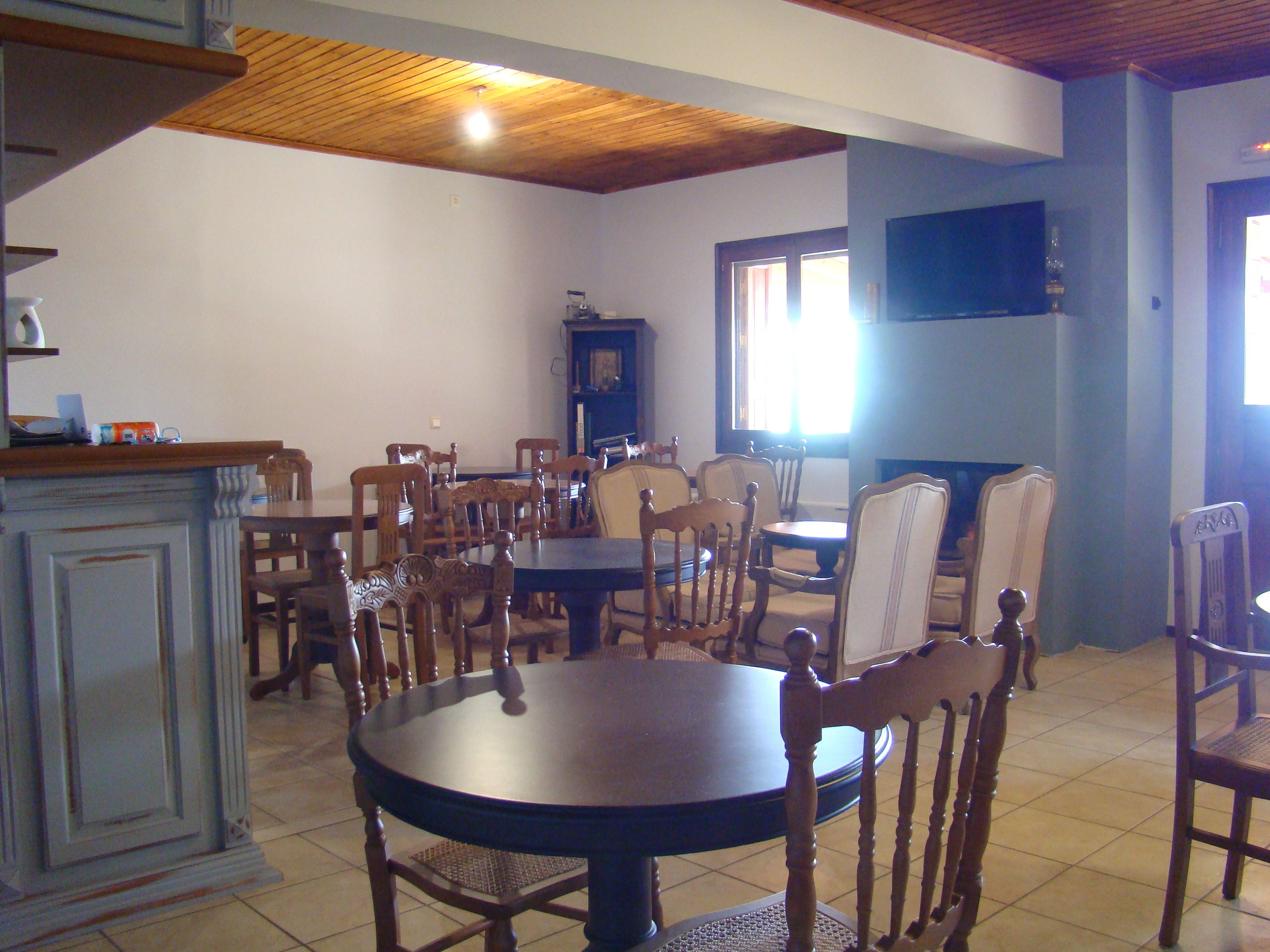 A dining area with a round table and multiple chairs, a television mounted on the wall, and a fireplace.