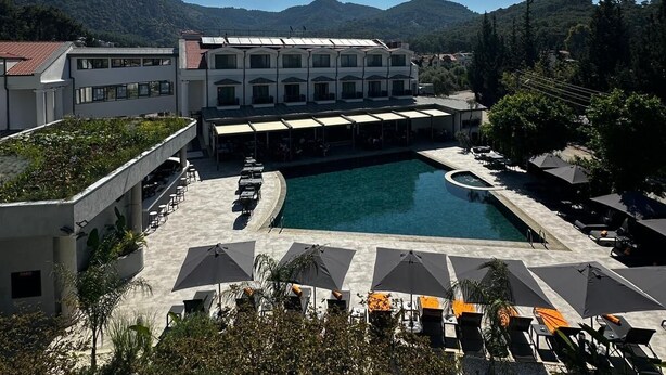 A hotel with a pool, outdoor seating, and a view of the mountains. - Göcek Lykia Resort Hotel (Fethiye)