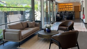 A modern hotel lobby with a sofa, chairs, a coffee table, and a bar area. - Göcek Lykia Resort Hotel (Fethiye)