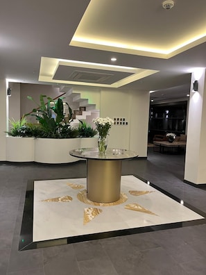 Eine moderne Lobby mit rundem Tisch, Topfpflanzen und einer Treppe.