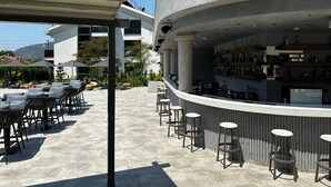An outdoor bar area with seating and a curved counter. - Göcek Lykia Resort Hotel (Fethiye)