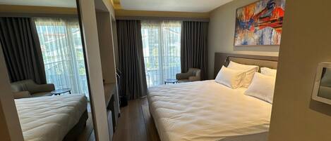 Habitación de hotel con dos camas, un espejo grande, un cuadro y vistas al exterior.