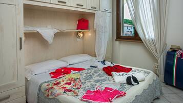 Ein Schlafzimmer mit einem Bett, einem Kleiderschrank, einem Fenster mit Vorhängen und einem Koffer.