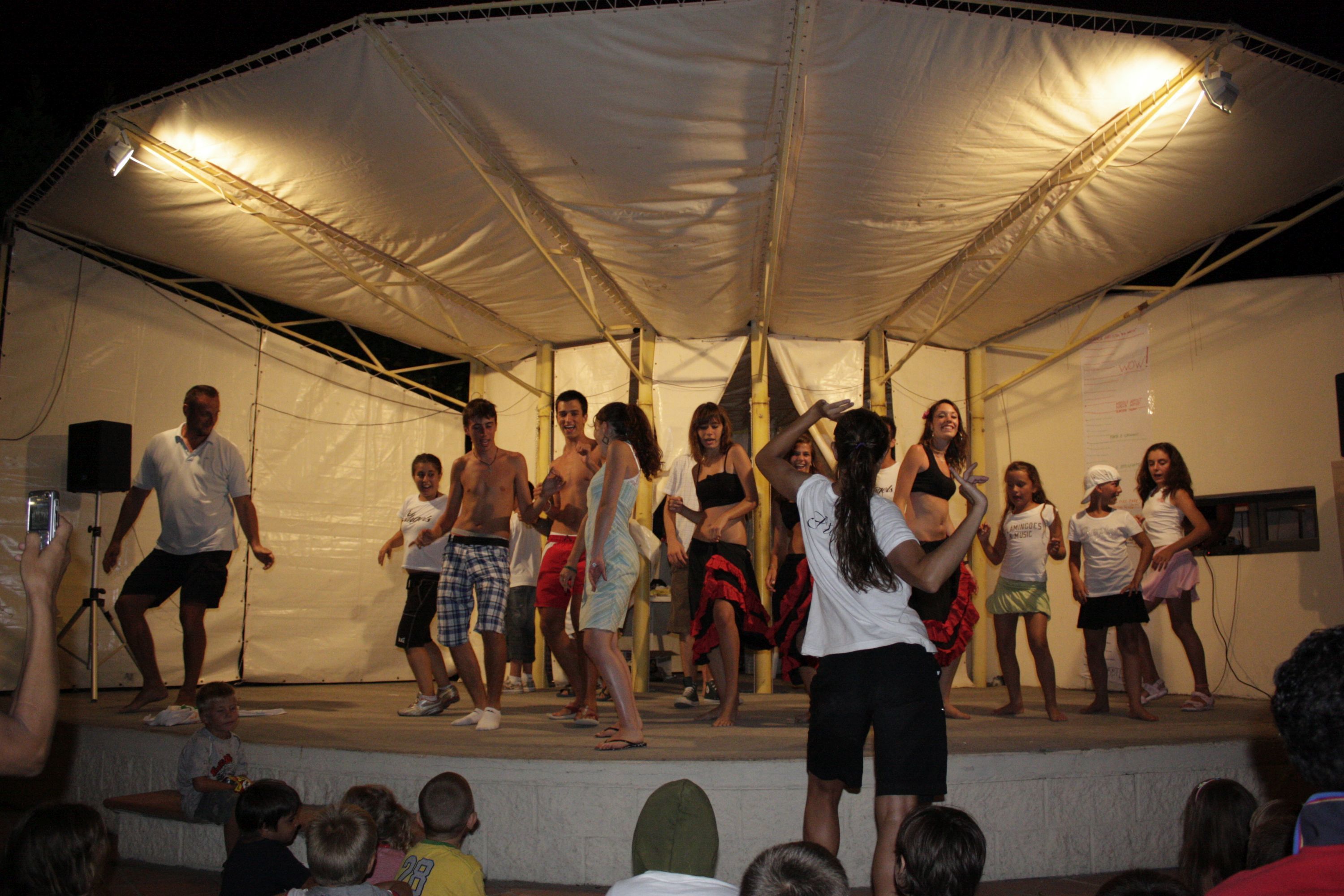 A group of people on a stage under a tent.