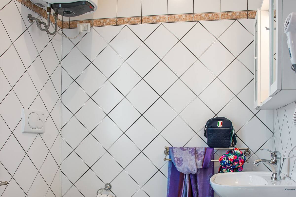 A bathroom with a toilet, bidet, sink, and a towel rack with towels.