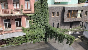 A multi-story building with a large ivy-covered tree in the foreground.