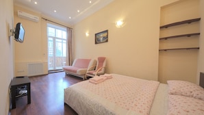 A bedroom with a bed, a chair, a TV, and a window.