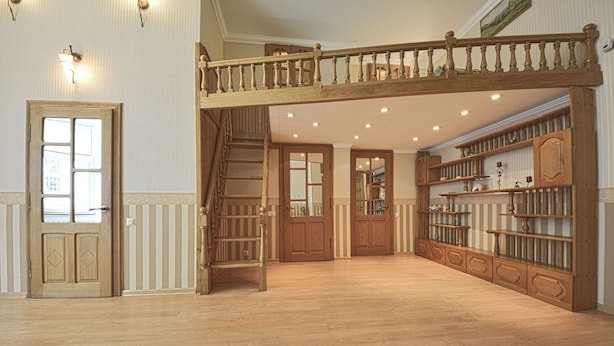 A spacious room with a wooden staircase, built-in bookshelves, and a large door.