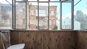 A room with wooden paneling and large windows overlooking a multi-story building with balconies.