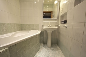 A bathroom with a bathtub, sink, and mirror.