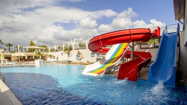 A pool with multiple slides, including a rainbow-colored one, and a building with a sign that reads "Billionaire's Club". - Dalaman Airport Lykia Thermal & Spa Hotel (Dalaman)