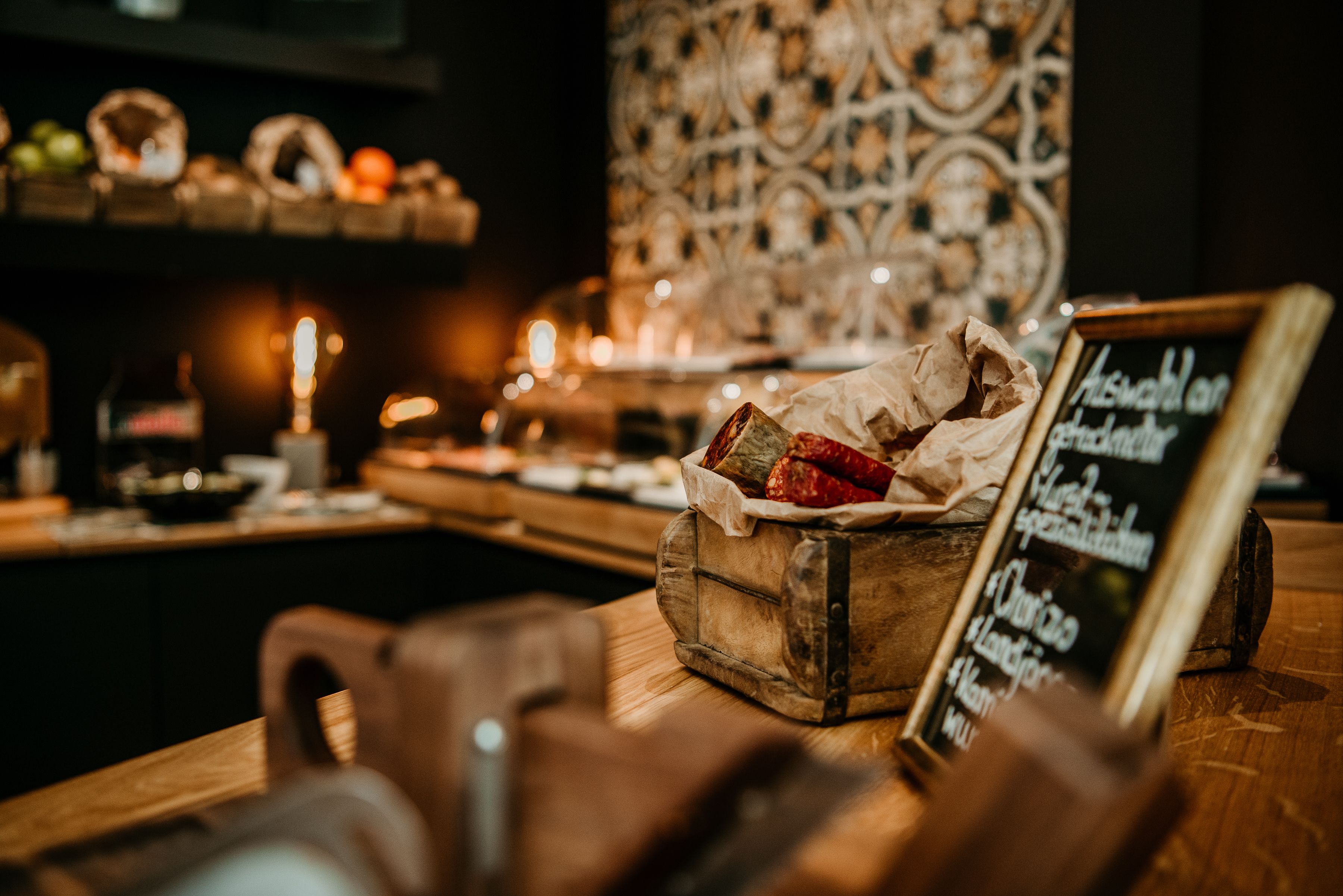 A wooden counter with a rustic appearance, a chalkboard menu, and a decorative wall in the background.