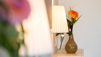 A lamp with a white shade and a vase with flowers on a white surface.