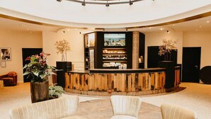 A lobby with a curved reception desk, seating area, and a large TV screen.