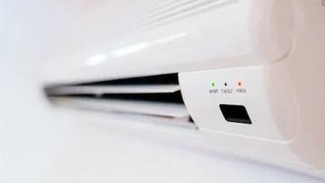 A white air conditioning unit with three indicator lights and a small ventilation grille.