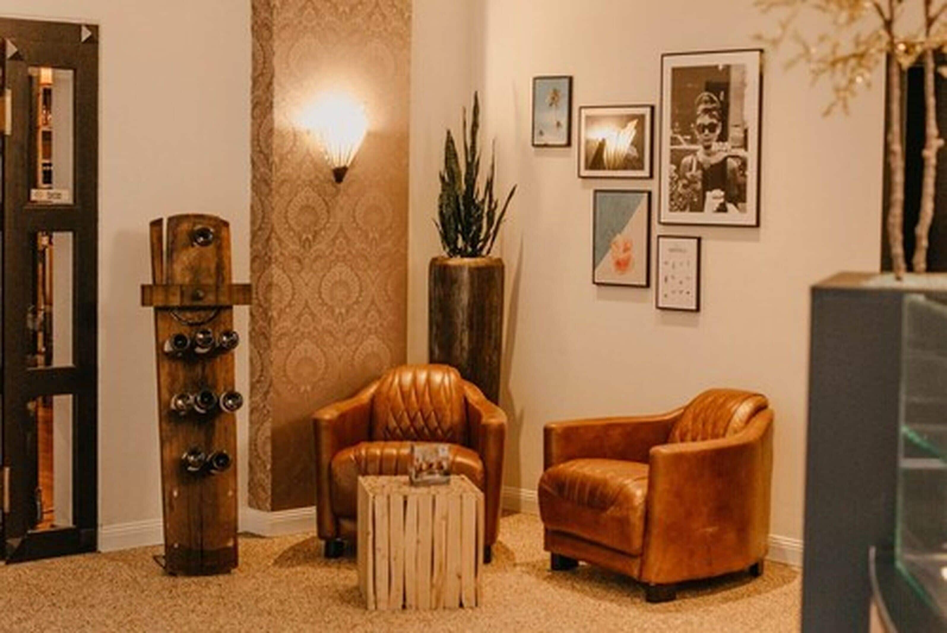 Un salon avec un fauteuil en cuir marron, une table basse en bois et un grand lampadaire.