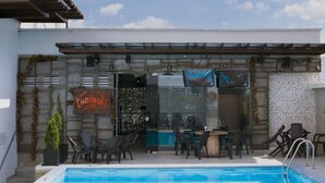 Zona junto a la piscina con mobiliario exterior y un bar.