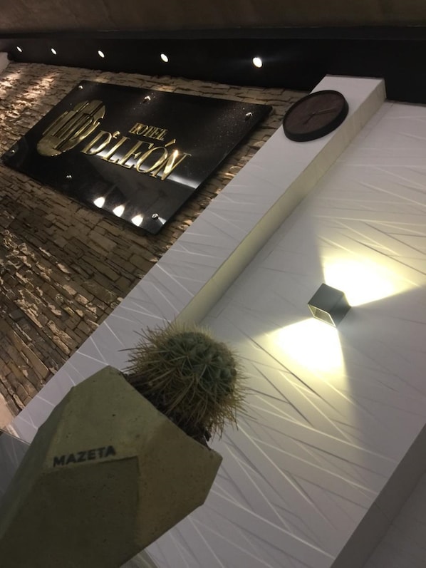 A modern hotel entrance with a black sign reading "HOTEL DEL MONTE" and a clock.