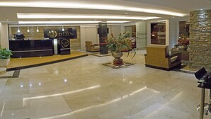 Un vestíbulo de hotel con mostrador de recepción, zona de estar y una planta decorativa.