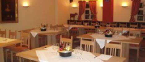 A dining area with multiple tables and chairs, some with tablecloths.