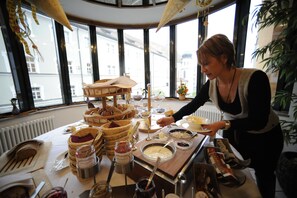 A buffet table with various food items and a person serving. - Hotel Theresientor (Straubing)