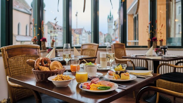 Una mesa de comedor servida con diversos platos, vasos y una cesta de pan.