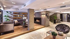 Een moderne lobby met een open haard, zithoek en een trap.
