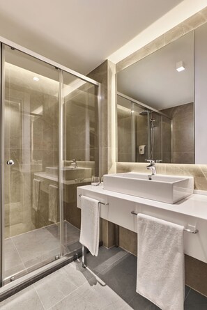 A modern bathroom with a glass-enclosed shower, a double sink vanity, and a large mirror.