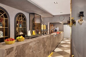 A marble reception desk with fruit bowls, a clock, and a wall-mounted lamp. - The New Hotel Zeybek (Izmir)