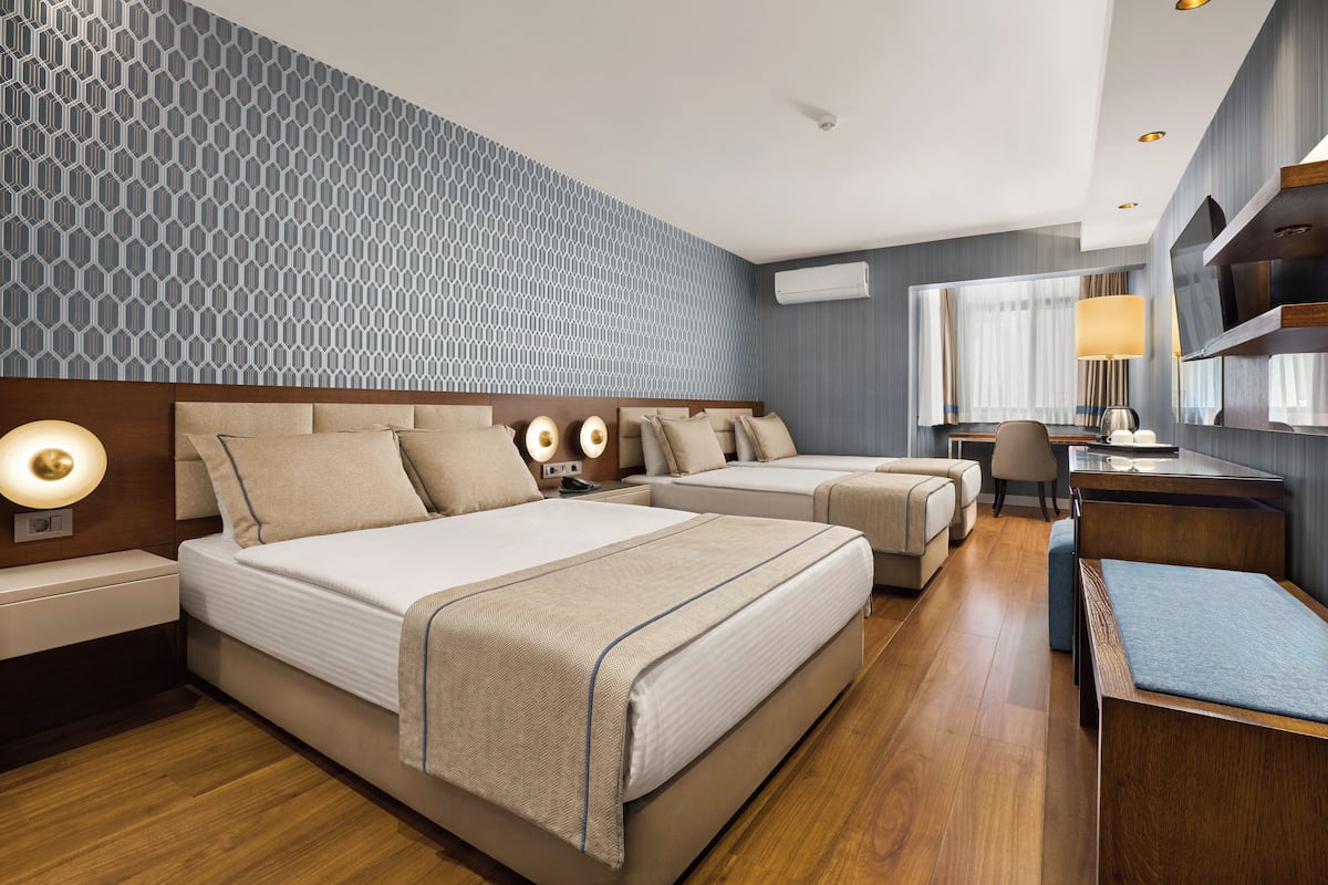 A hotel room with two beds, a desk, a chair, and a TV.