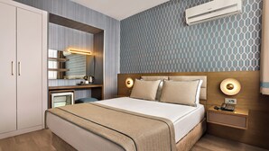 Een moderne hotelkamer met een bed, nachtkastje, en een ingebouwd bureau met spiegel.