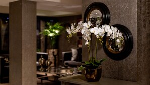 Een modern interieur met een pot orchidee op een tafel, een spiegel en een plant op de achtergrond.