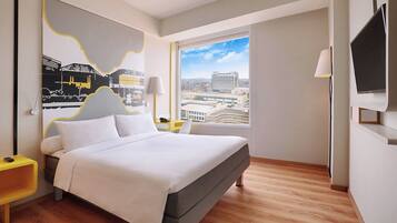 Un hotel moderno con una cama grande, vistas a la ciudad, un televisor de pantalla plana y una decoración minimalista.