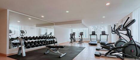 A gym with treadmills, elliptical machines, and a bench press.