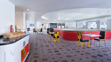 A modern restaurant with a central counter, multiple tables, and chairs.