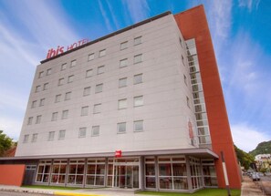 A modern hotel building with a flat facade, multiple windows, and a prominent red sign at the top. - ibis Montenegro (Montenegro)