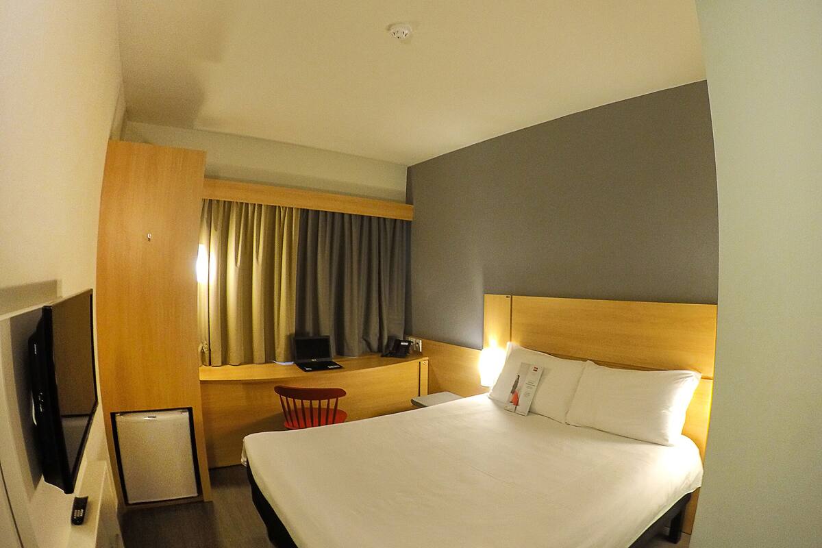 Una habitación de hotel con una cama grande, un escritorio con computadora, una silla y un televisor.