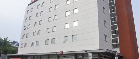 A multi-story hotel with a modern design, featuring a prominent entrance with glass doors and a signboard.