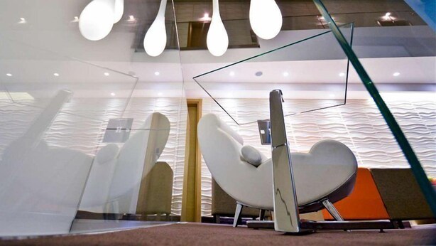 A modern interior with a unique seating area featuring a heart-shaped chair and contemporary lighting fixtures. - Artloft Hotel (Nis)