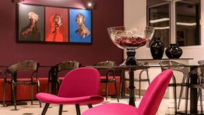 A modern dining area with a glass table, a bowl of fruit, and vibrant artwork on the wall. - Artloft Hotel (Nis)