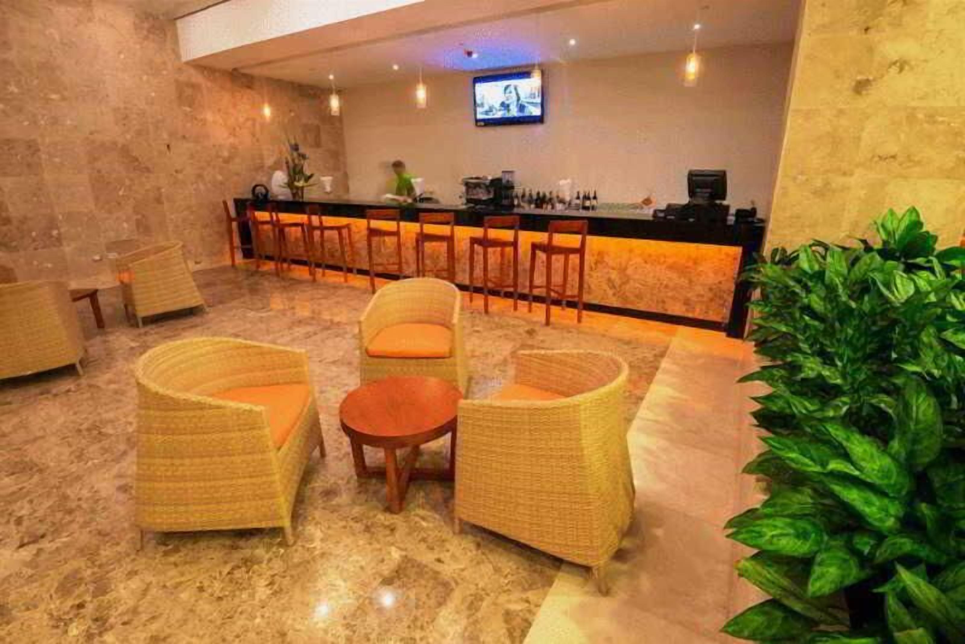 A lobby with wicker furniture, a bar area, and a television screen.