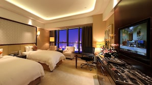 A hotel room with two beds, a desk, a TV, and a view of the city at night. - Wyndham Grand Plaza Royale Changsheng Jiangyin (Wuxi)