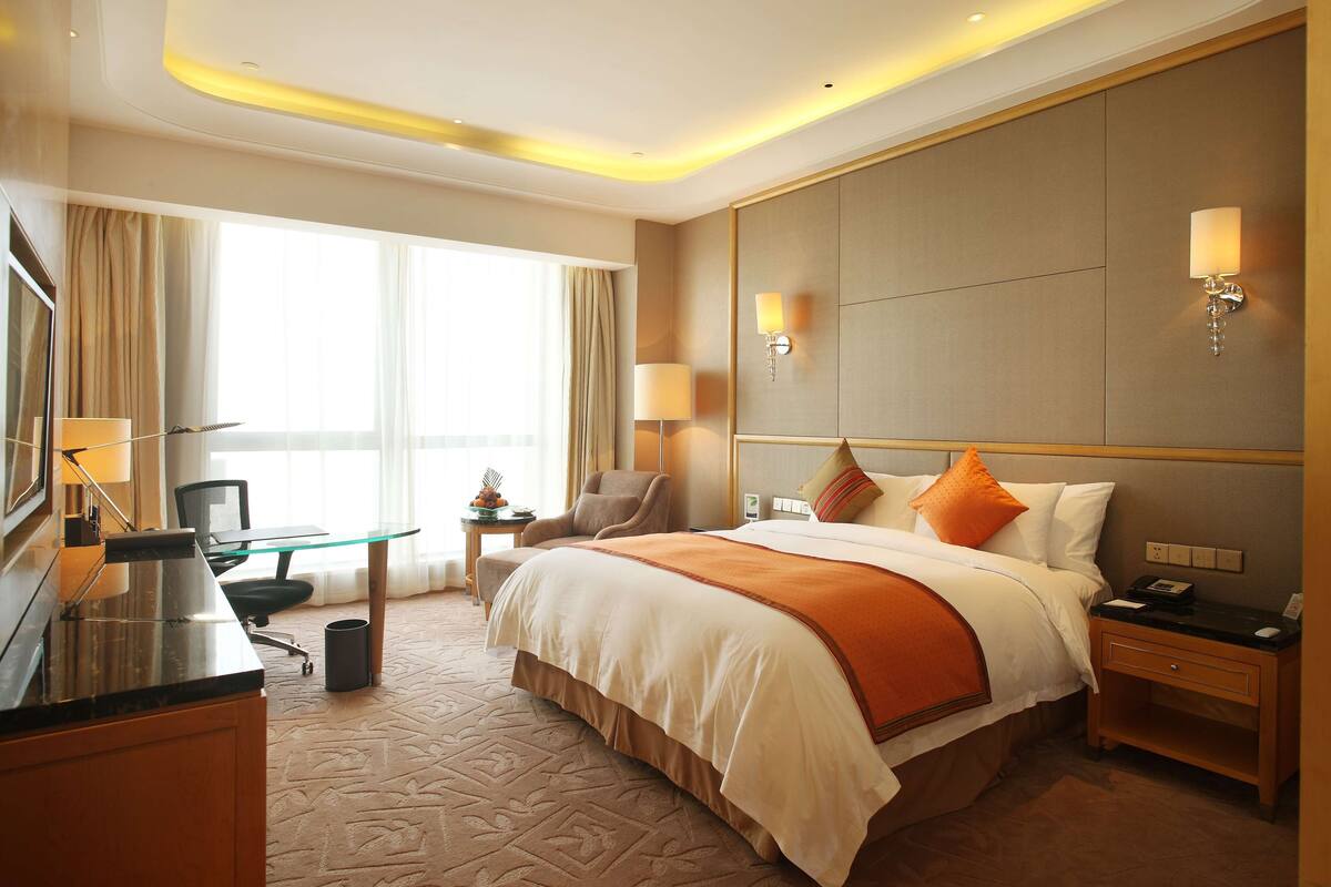 Une chambre d’hôtel avec un grand lit, un bureau, une chaise, une télévision et un mini-bar.