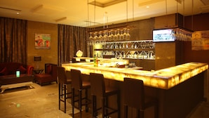 A bar area with a marble countertop, bar stools, and a television mounted on the wall. - Wyndham Grand Plaza Royale Changsheng Jiangyin (Wuxi)