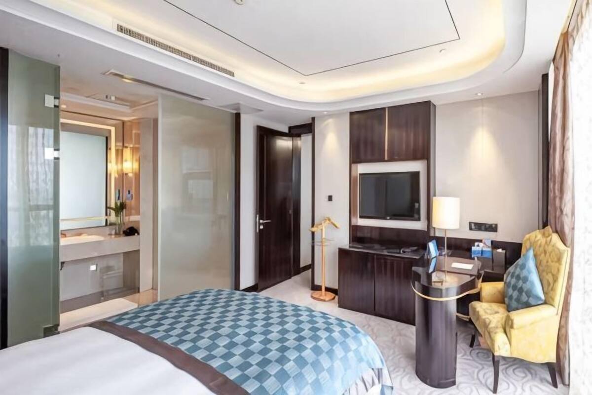Une chambre d’hôtel comprenant un lit, un bureau, une télévision, une chaise et un miroir.