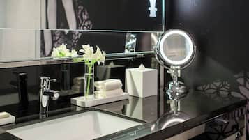 Un baño moderno con un espejo grande, un lavamanos de vidrio y toallas dobladas con cuidado.