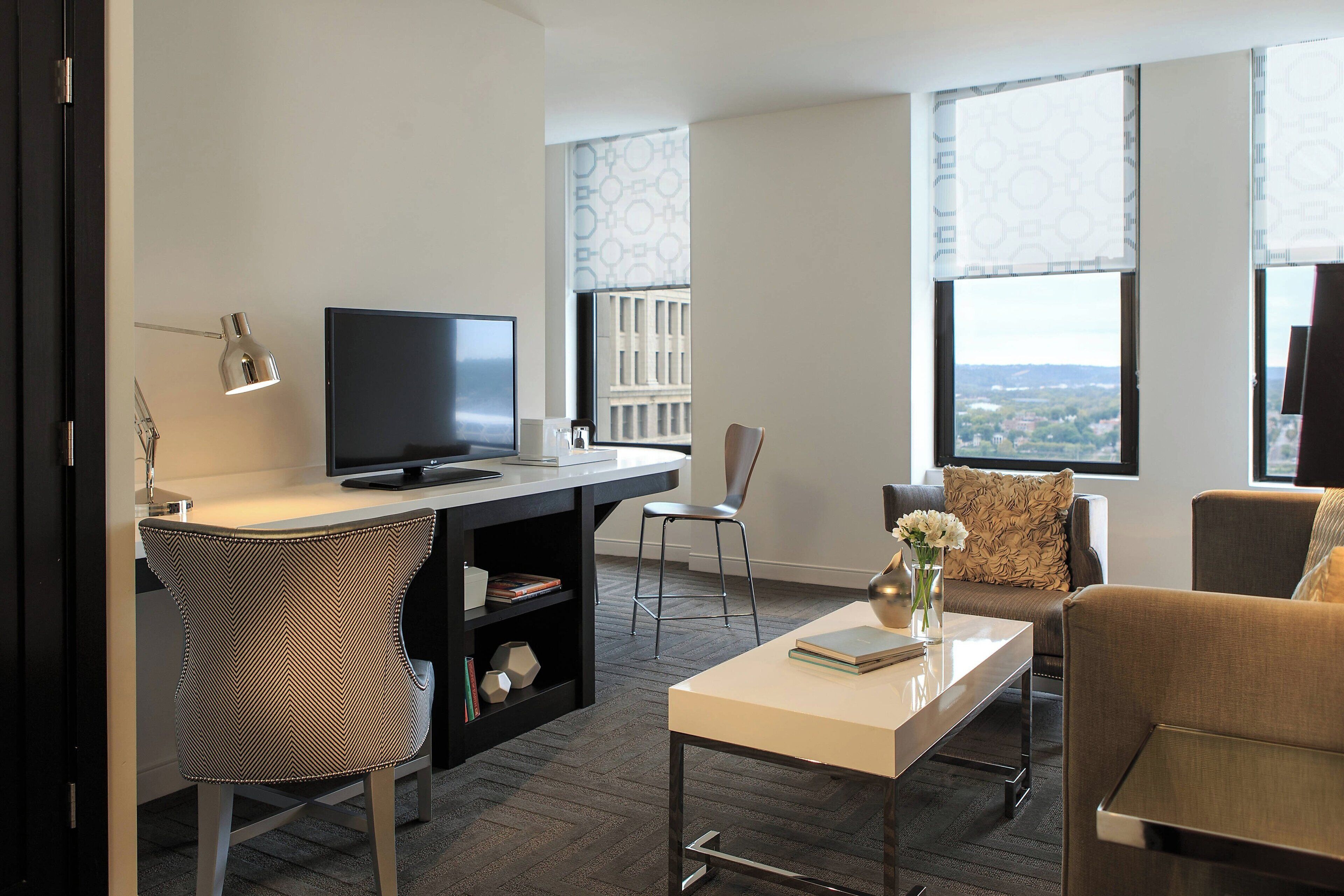 A modern living room with a flat-screen TV, a dining table, a sofa, and a chair.