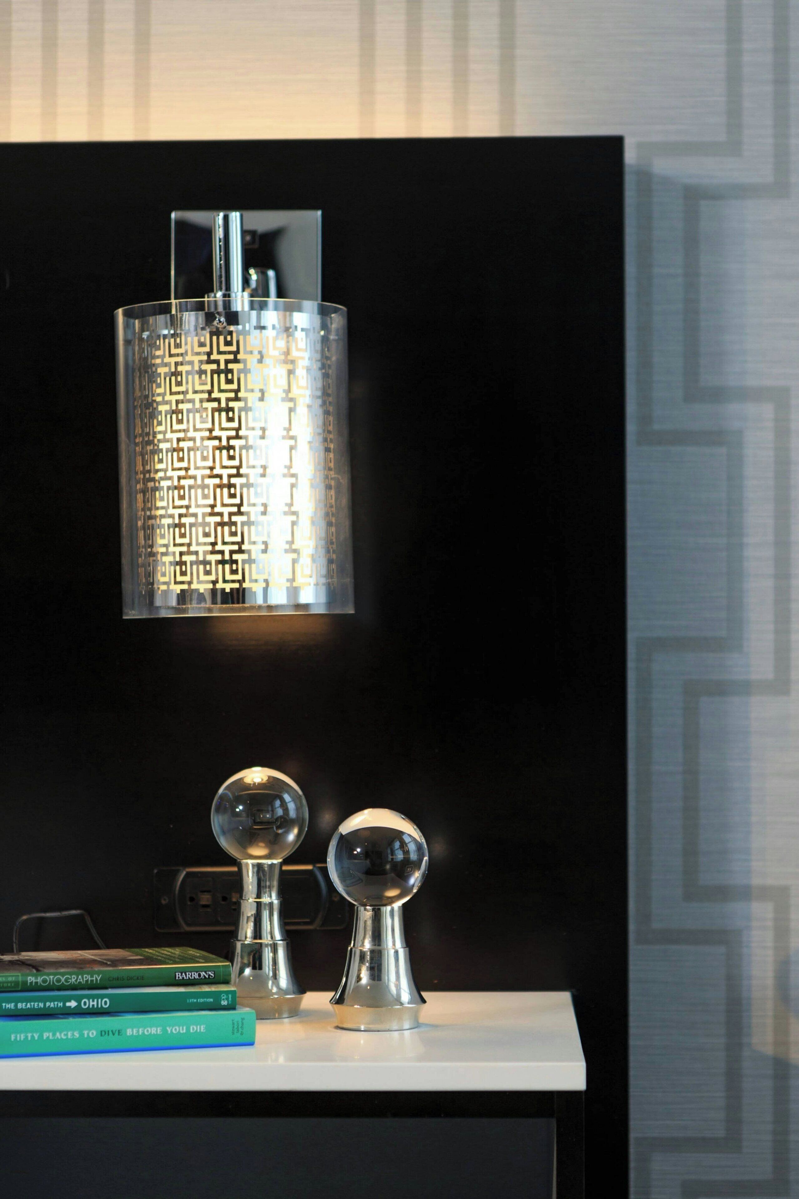 A modern interior with a decorative wall-mounted light fixture, a white console table, and a geometric patterned wall.