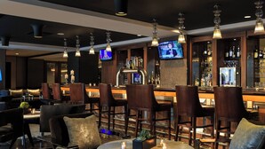 Eine Bar mit verschiedenen Sitzgelegenheiten, einem Fernsehbildschirm und einer gut sortierten Bar.